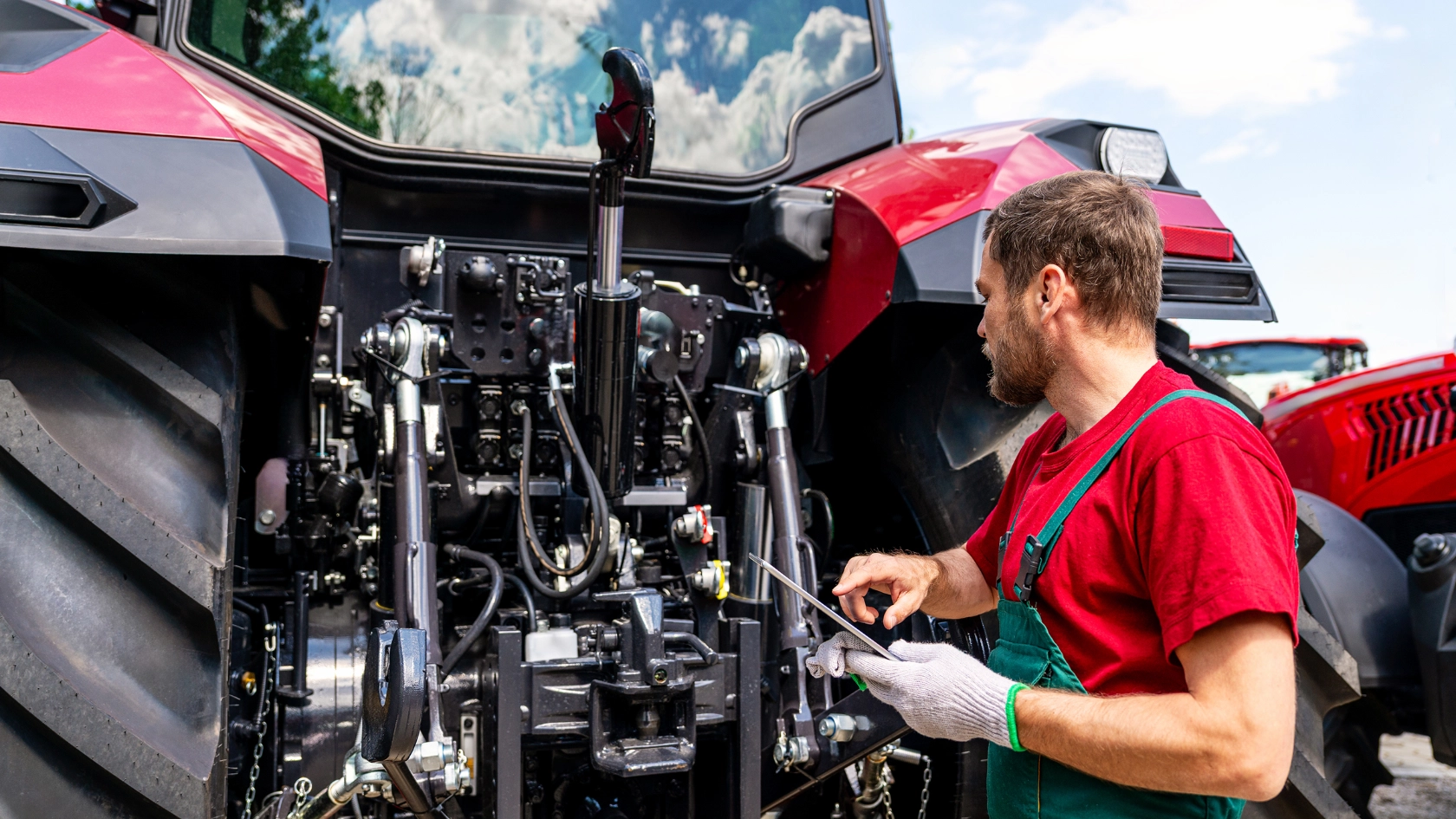 Ein männlicher Land- & Baumaschinenmechatroniker prüft einen Traktor mit einem Tablet
